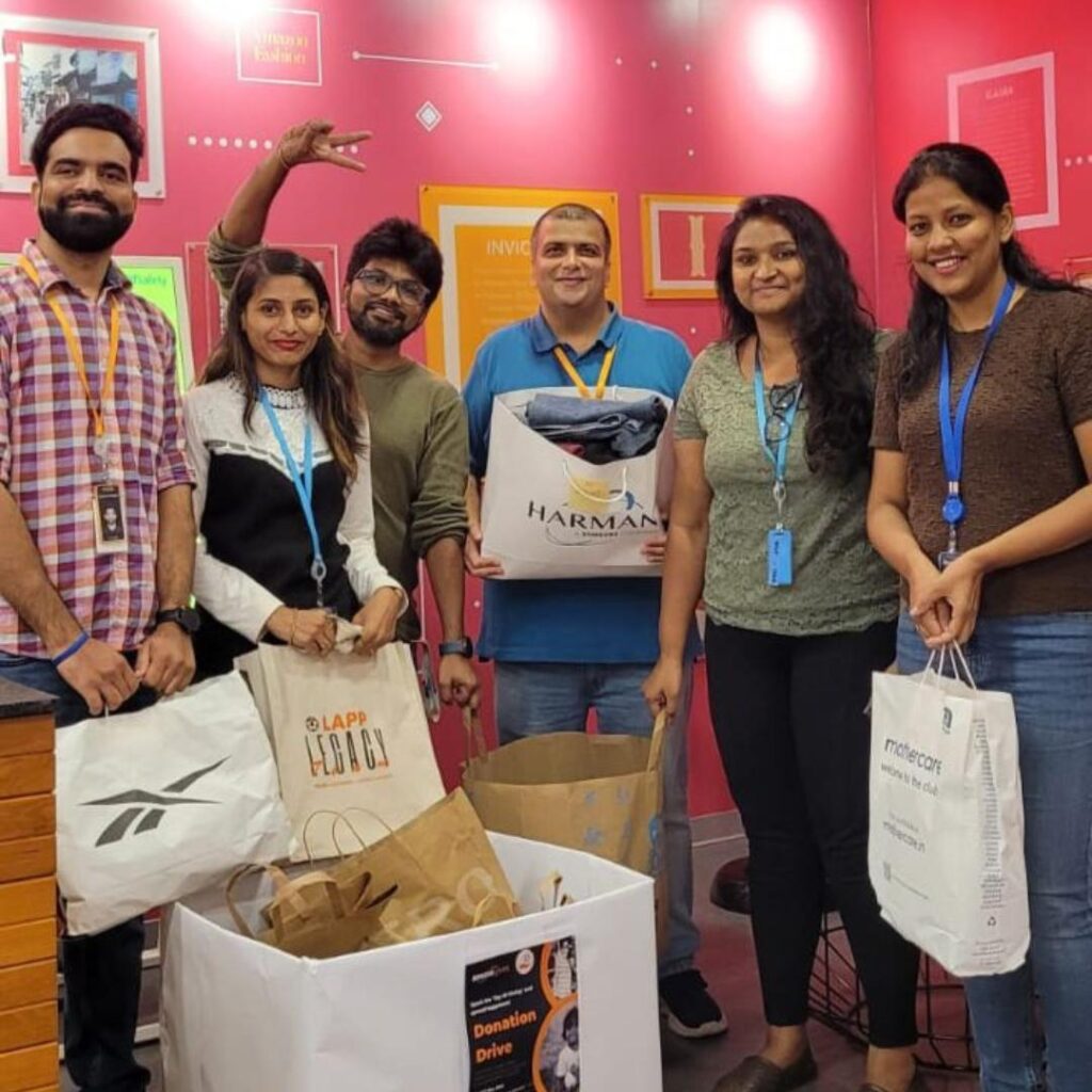 Amazon's Global Volunteering Month: Happy employees in a donation drive with Share At Door Step, celebrating together.